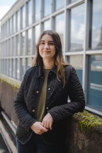 Woman leaning on a rock wall outside of a buidling